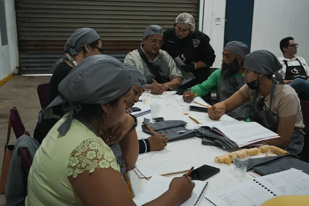 Grupo de personas con boinas revisando documentos en una mesa de trabajo